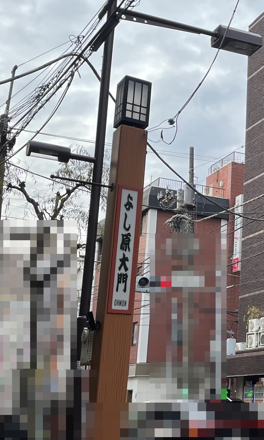 現在の吉原大門跡に立つ、よし原大門と書かれた灯柱。周辺の商業表示はモザイク加工済み
